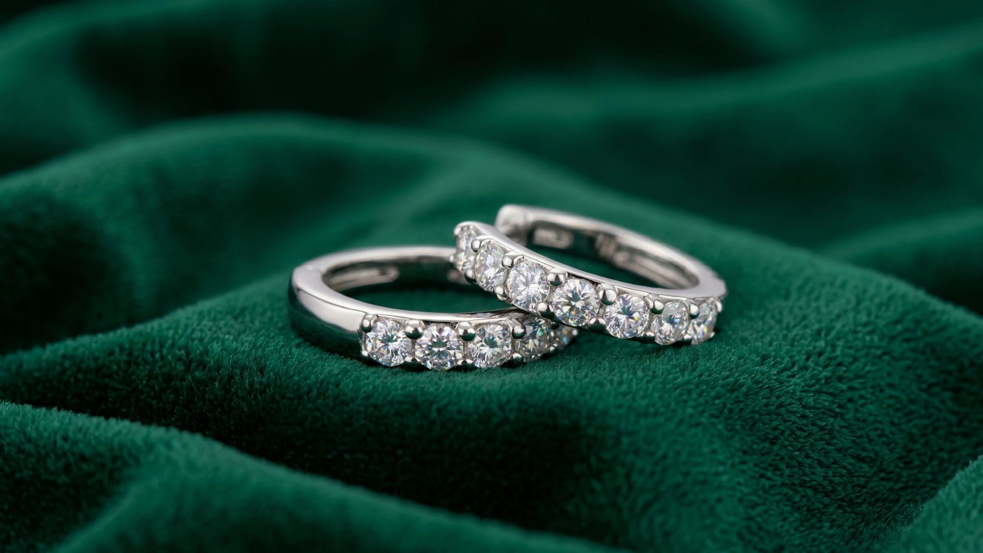 Close-up luxury image of elegant silver crystal rings placed on rich emerald green velvet fabric representing premium craftsmanship, timeless elegance, and sophisticated imitation jewellery by ANKKSHMI.
