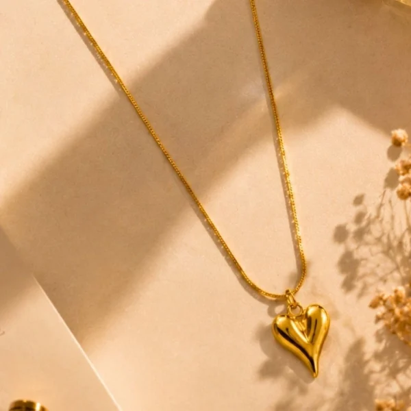 Gold heart pendant necklace with anti-tarnish 18K gold-plated chain on a beige luxury background