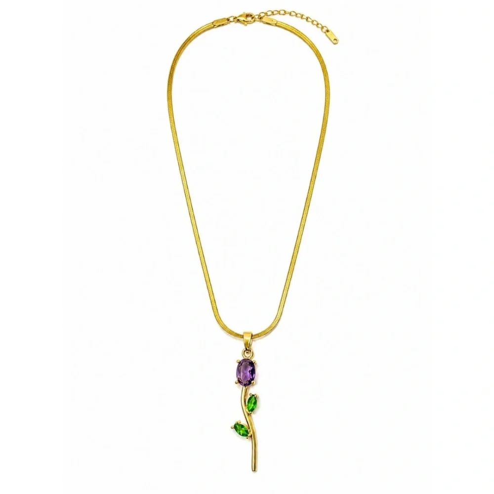 Gold floral pendant necklace with purple and green gemstone accents on a white background